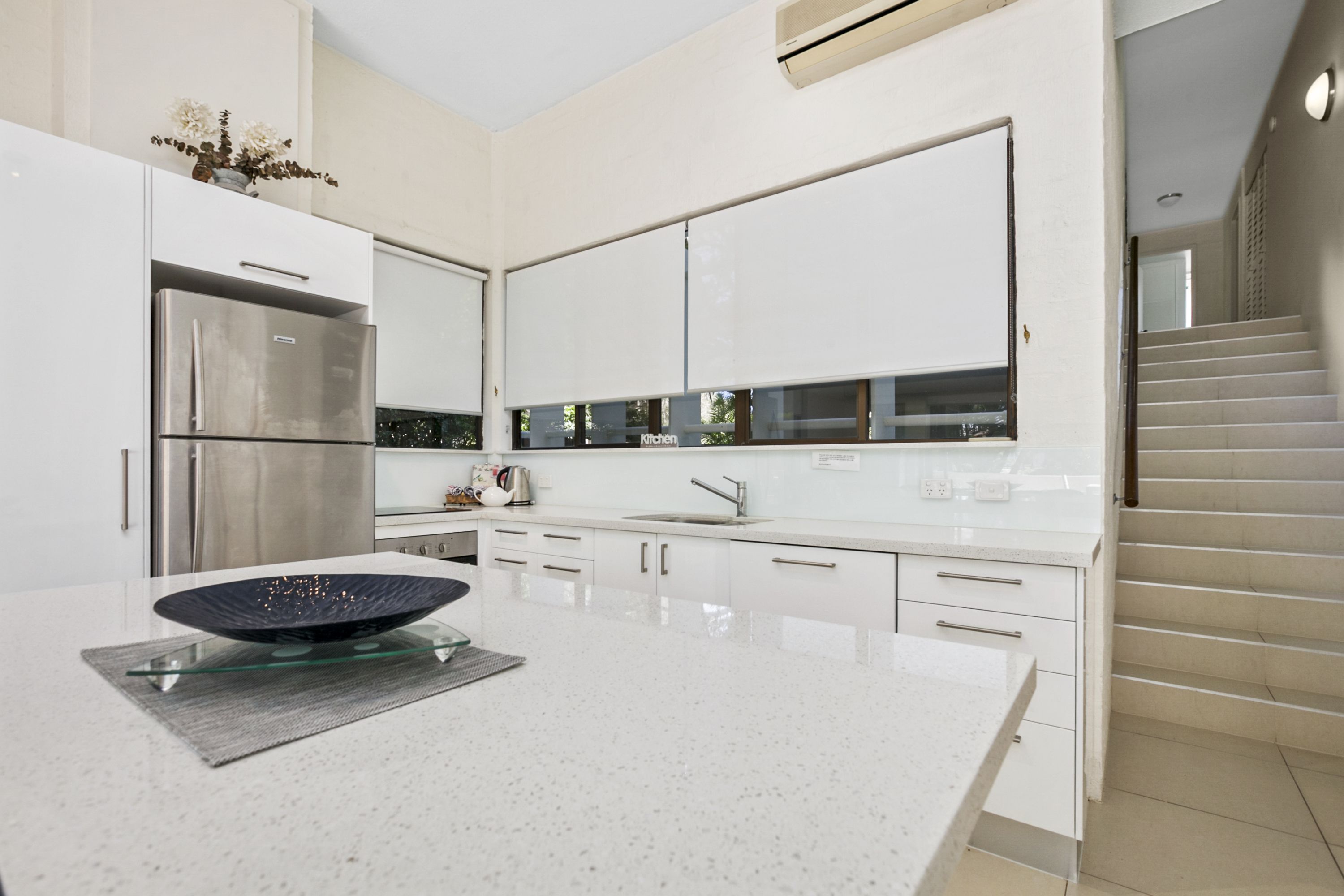 Una cocina moderna con armarios blancos, electrodomésticos de acero inoxidable y una isla central con un bol de vidrio.