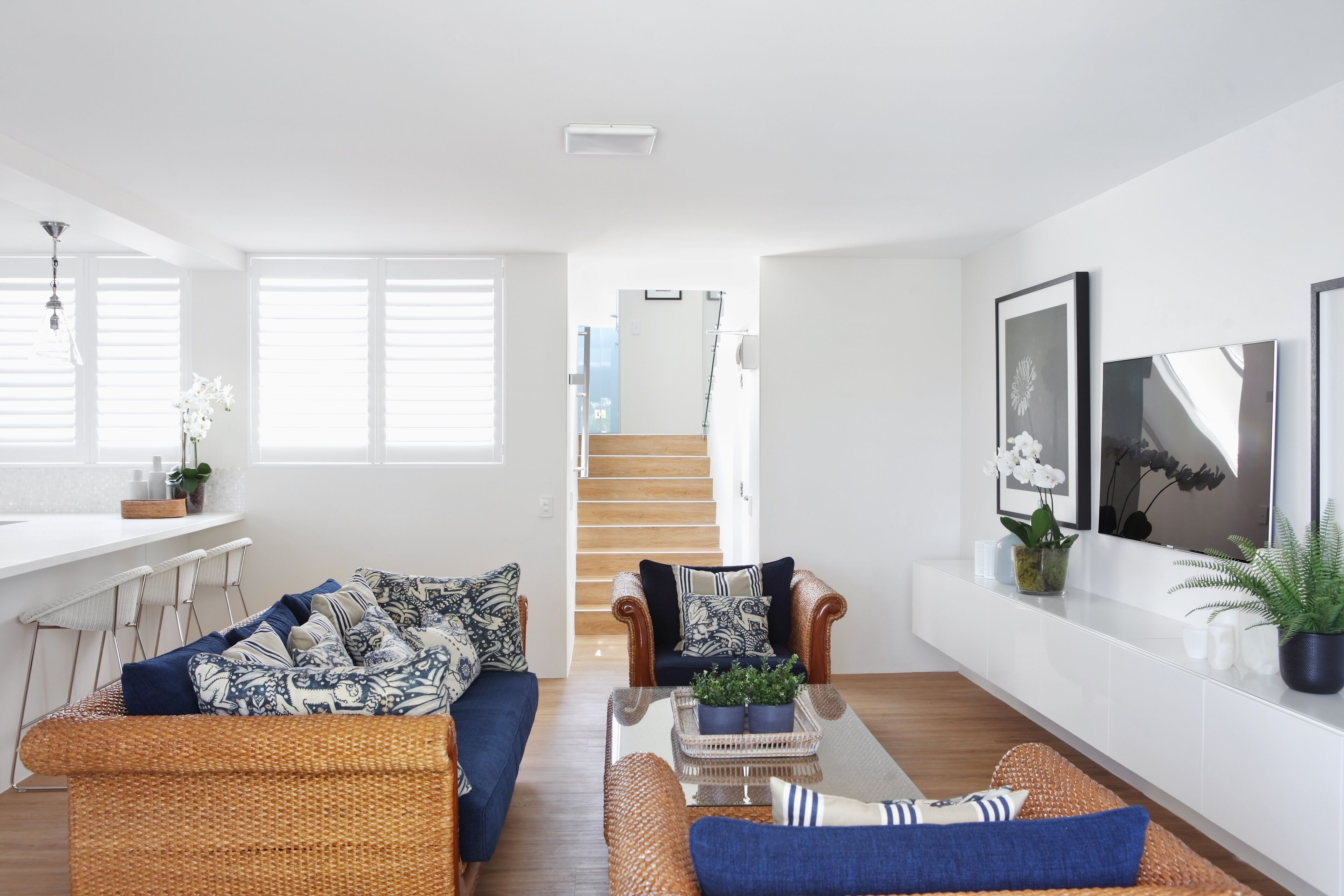 Una sala de estar moderna con sofás de mimbre, una mesa de centro y una escalera que lleva a un nivel superior.