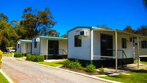 A row of mobile homes with a paved driveway and green landscaping. - Acclaim Swan Valley Tourist Park (West Swan)