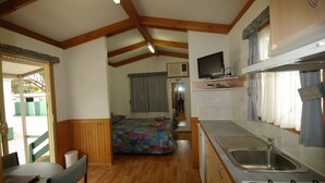 Ein kompaktes Wohnmobil-Interieur mit einer Küchenzeile, einem Bett und einer Essecke.