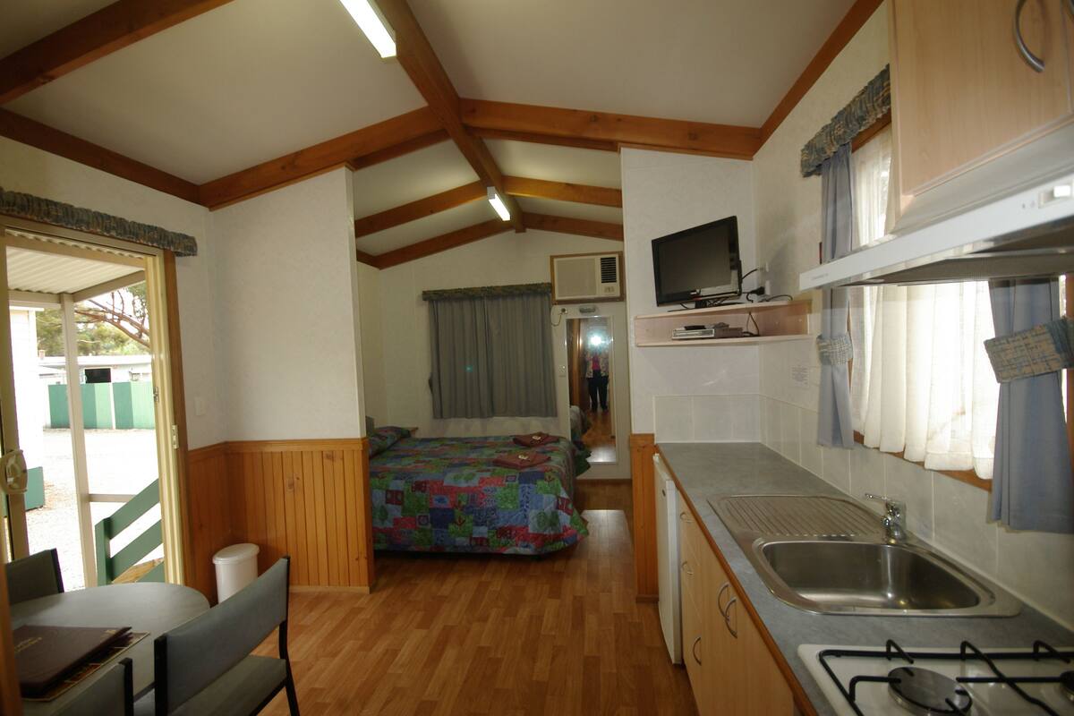 Interior compacto de autocaravana con kitchenette, cama y zona de comedor.