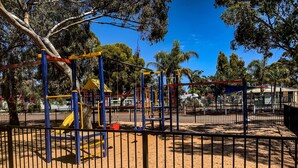 Ein Spielplatz mit einem umzäunten Bereich, Klettergerüsten und einer Rutsche.