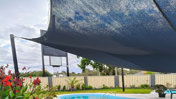 A pool area with a covered seating area, a pool, and surrounding greenery. - Wangaratta Motor Inn (Wangaratta)