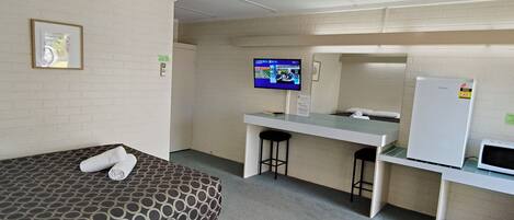 Habitación de hotel con dos camas, un escritorio, un televisor y un refrigerador.