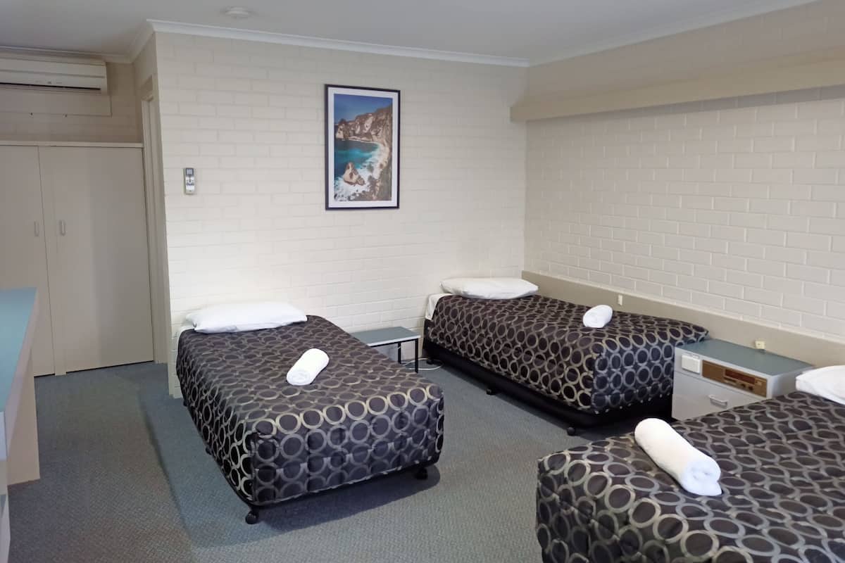 Quarto de hotel com duas camas de solteiro, uma escrivaninha e um guarda-roupa.