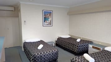 Een hotelkamer met twee eenpersoonsbedden, een bureau en een kledingkast.