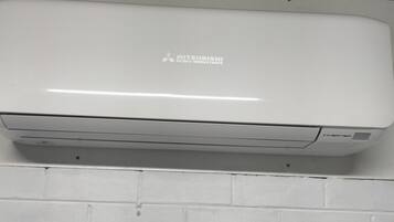 Un equipo de aire acondicionado Mitsubishi instalado en una pared de ladrillo blanco.