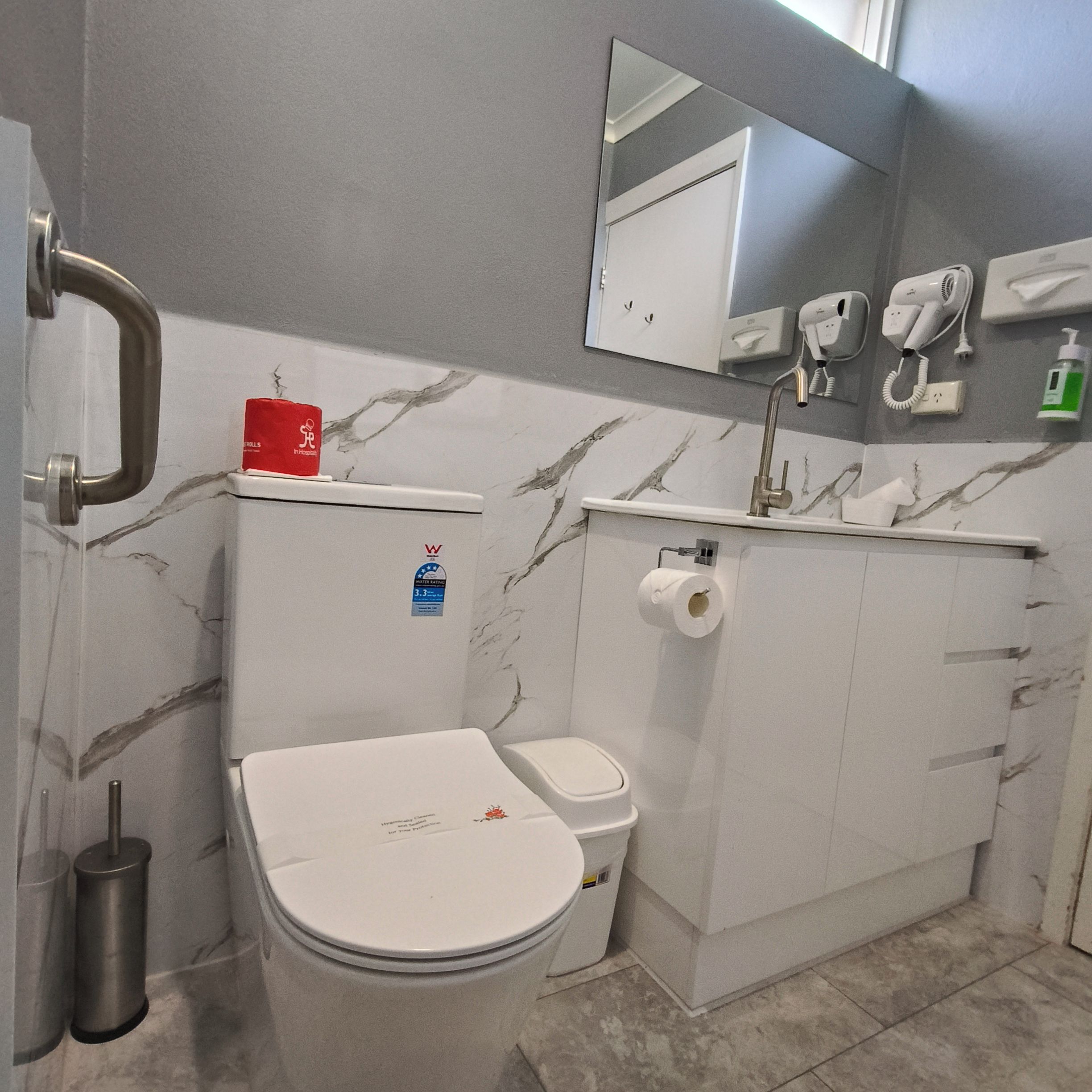 A bathroom with a toilet, bidet, and hand dryer.