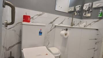 A bathroom with a toilet, bidet, and hand dryer.