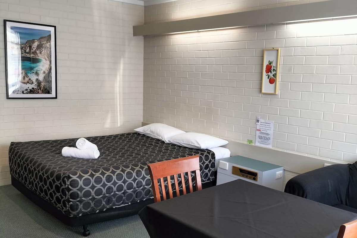 Quarto de hotel com duas camas, uma escrivaninha, uma cadeira e uma mesa.