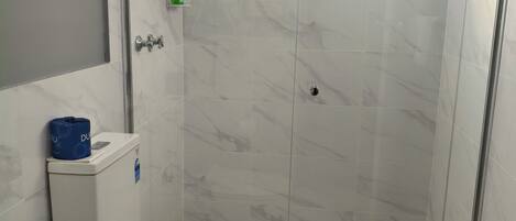 Un baño pequeño con inodoro, ducha y lavamanos.