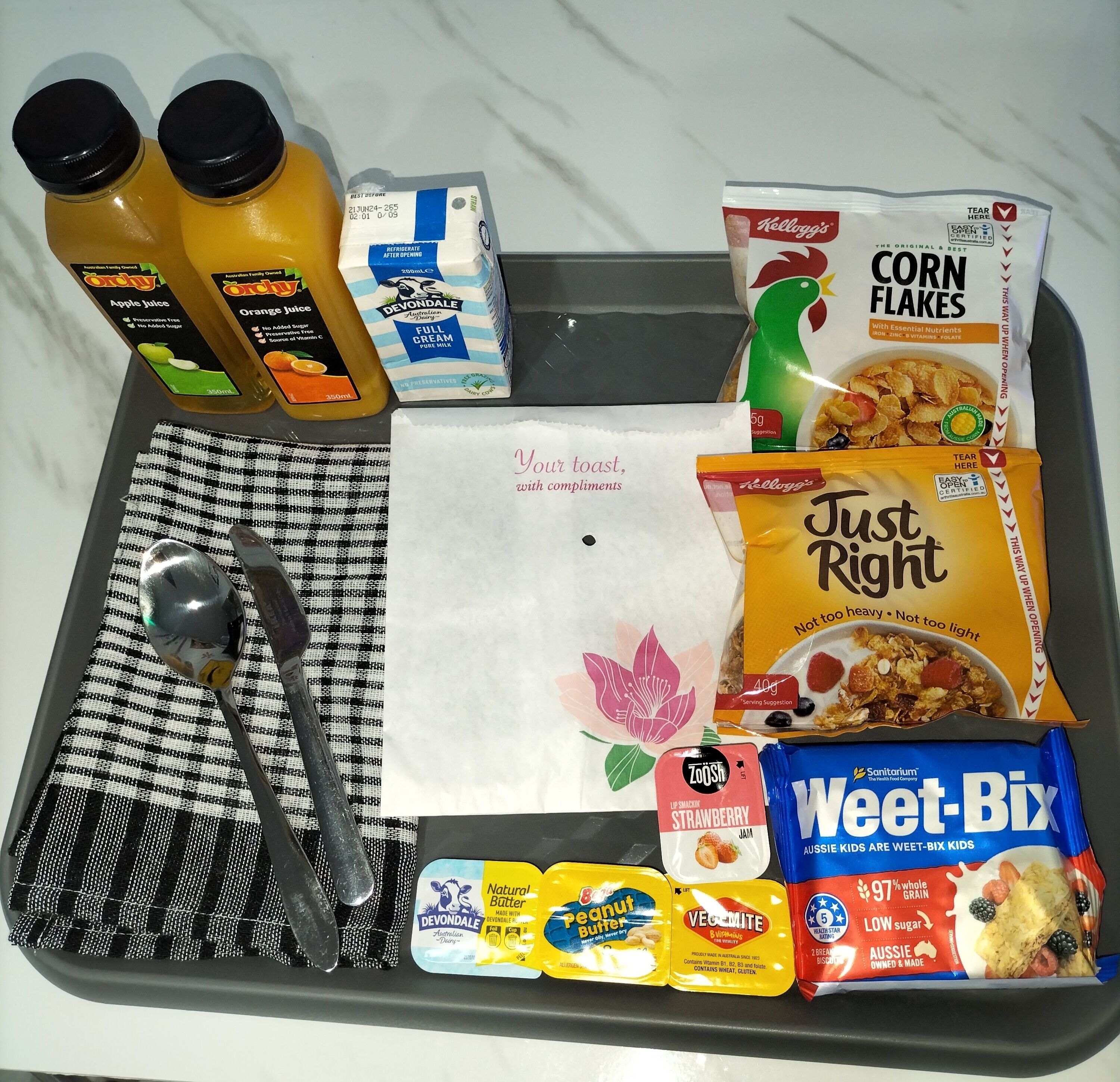Un vassoio con diversi articoli per la colazione, tra cui cereali, succo e creme spalmabili.