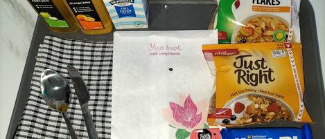 Una bandeja con diversos productos para el desayuno, como cereal, jugo y conservas.