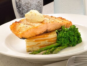 A plate with a piece of salmon, a scoop of butter, and asparagus. - Room Motel Kingaroy (Kingaroy)