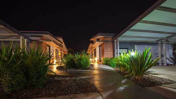 A modern hotel with a covered walkway, outdoor plants, and a starry night sky. - Room Motel Kingaroy (Kingaroy)