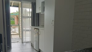 A hotel room with a bed, a desk, a wardrobe, and a view of the outside.