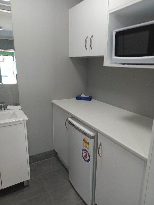 A compact kitchenette with a microwave, a small refrigerator, and a sink.