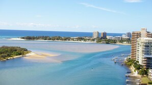Un paisaje urbano costero con un puerto deportivo, una playa y edificios altos.