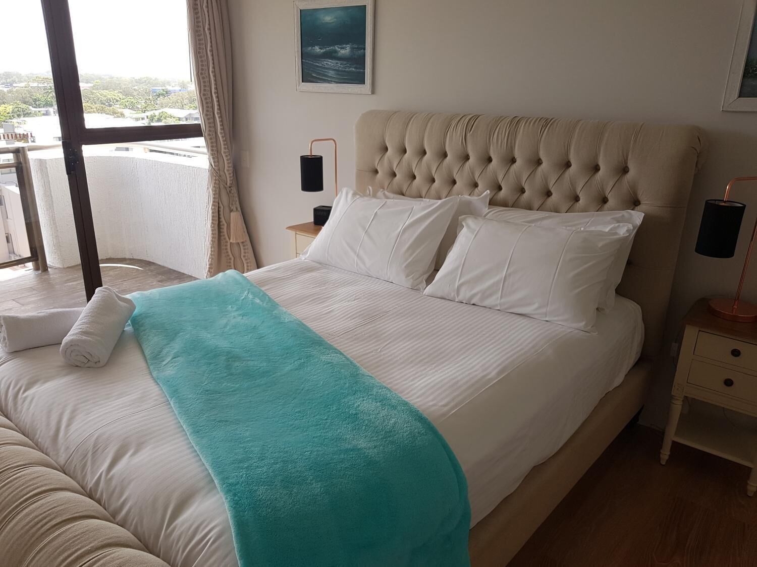 Un llit ben fet amb llençols d'un color maragda, almoinades blanques i un capçal amb botonades.