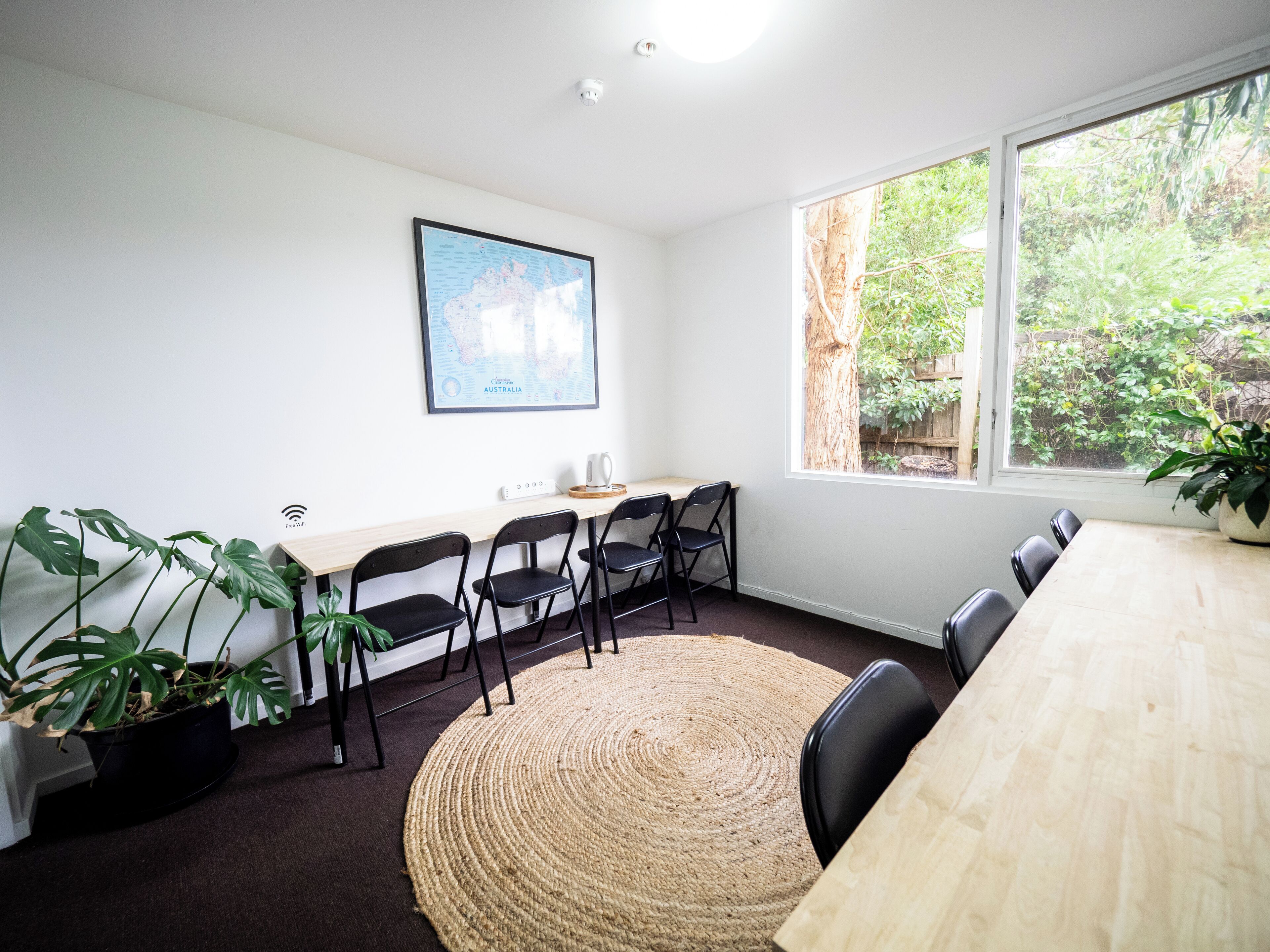 A conference room with a large window, a map on the wall, and a wooden table.