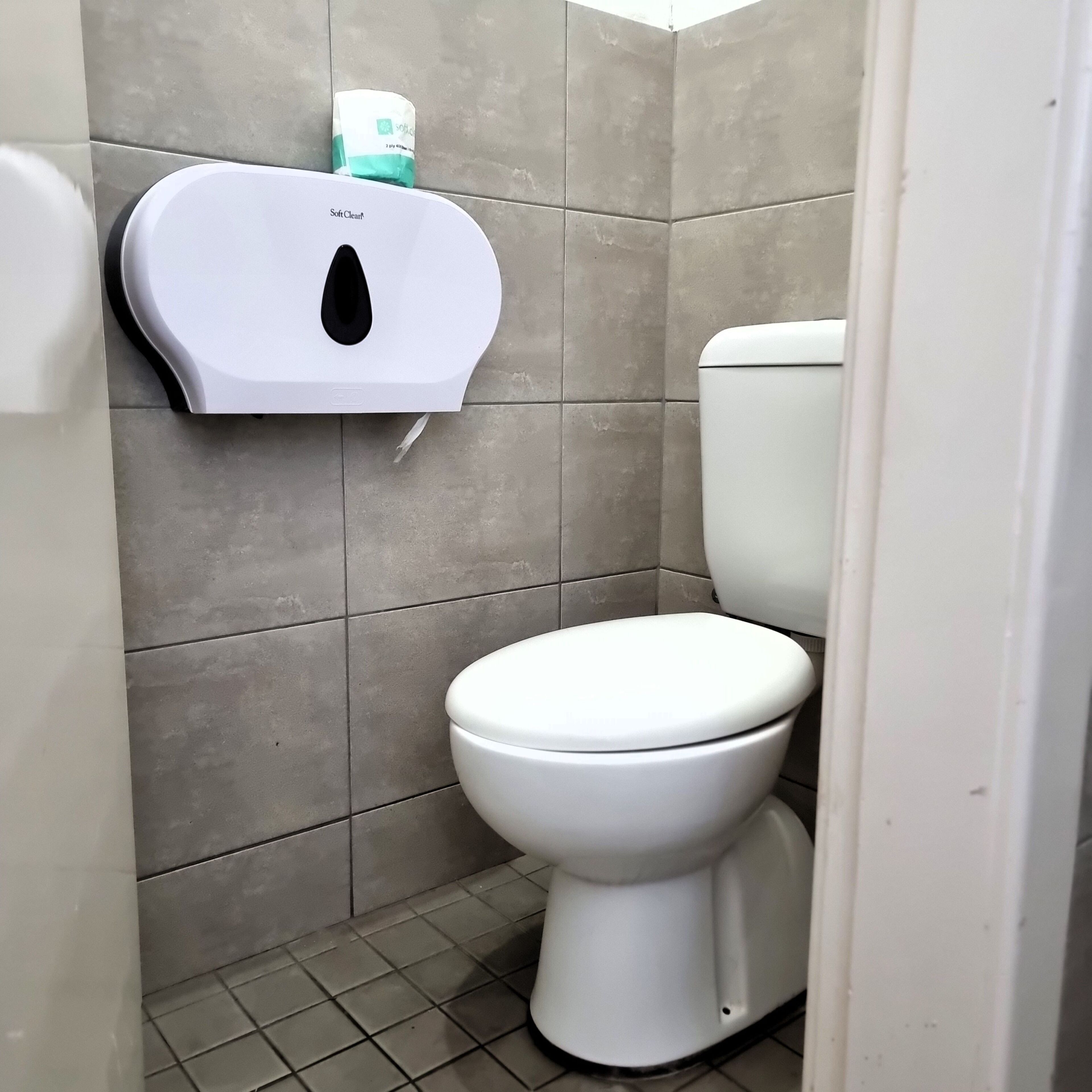Bagno con un water, un asciugatore di mani e un dispenser di carta.