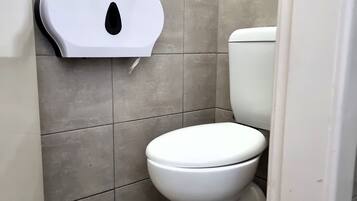 Bagno con un water, un asciugatore di mani e un dispenser di carta.