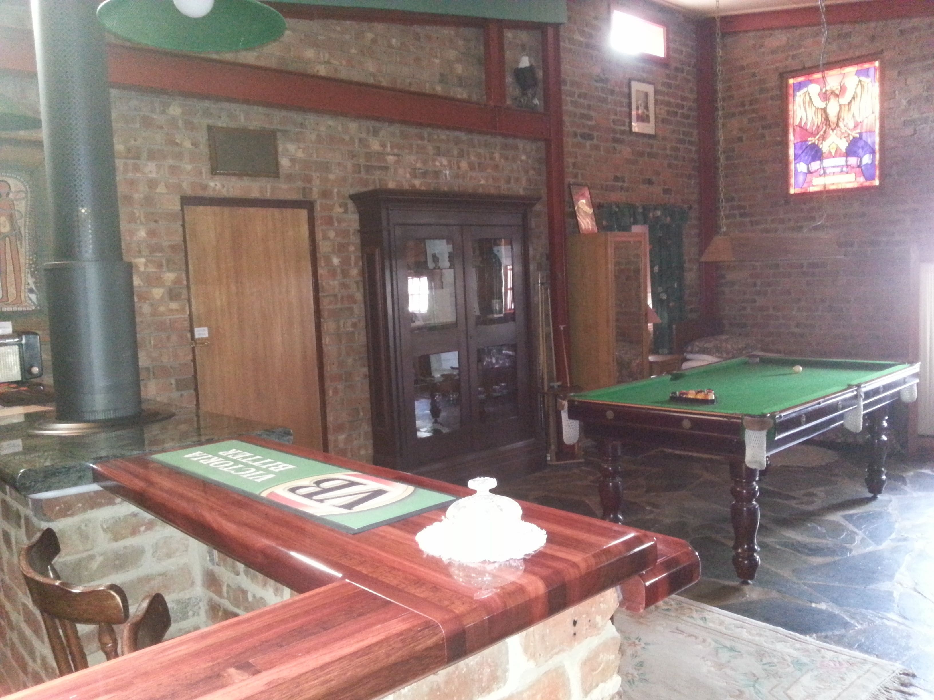 Une salle de billard équipée d’une table de billard, de meubles en bois et d’un mur en briques.