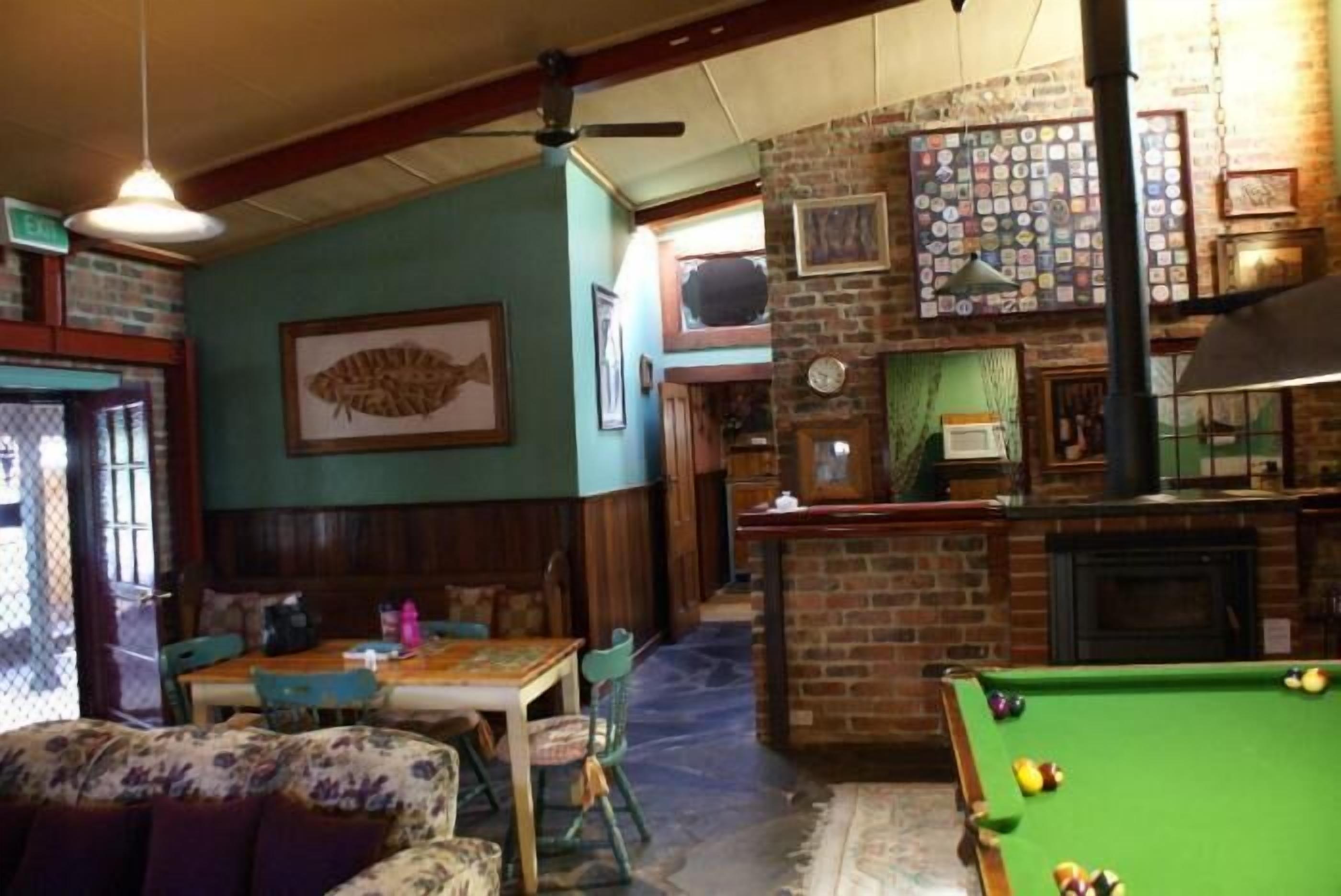 A cozy bar area with a pool table, wooden furniture, and a brick wall with various decorations.