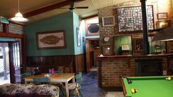 A cozy bar area with a pool table, wooden furniture, and a brick wall with various decorations.