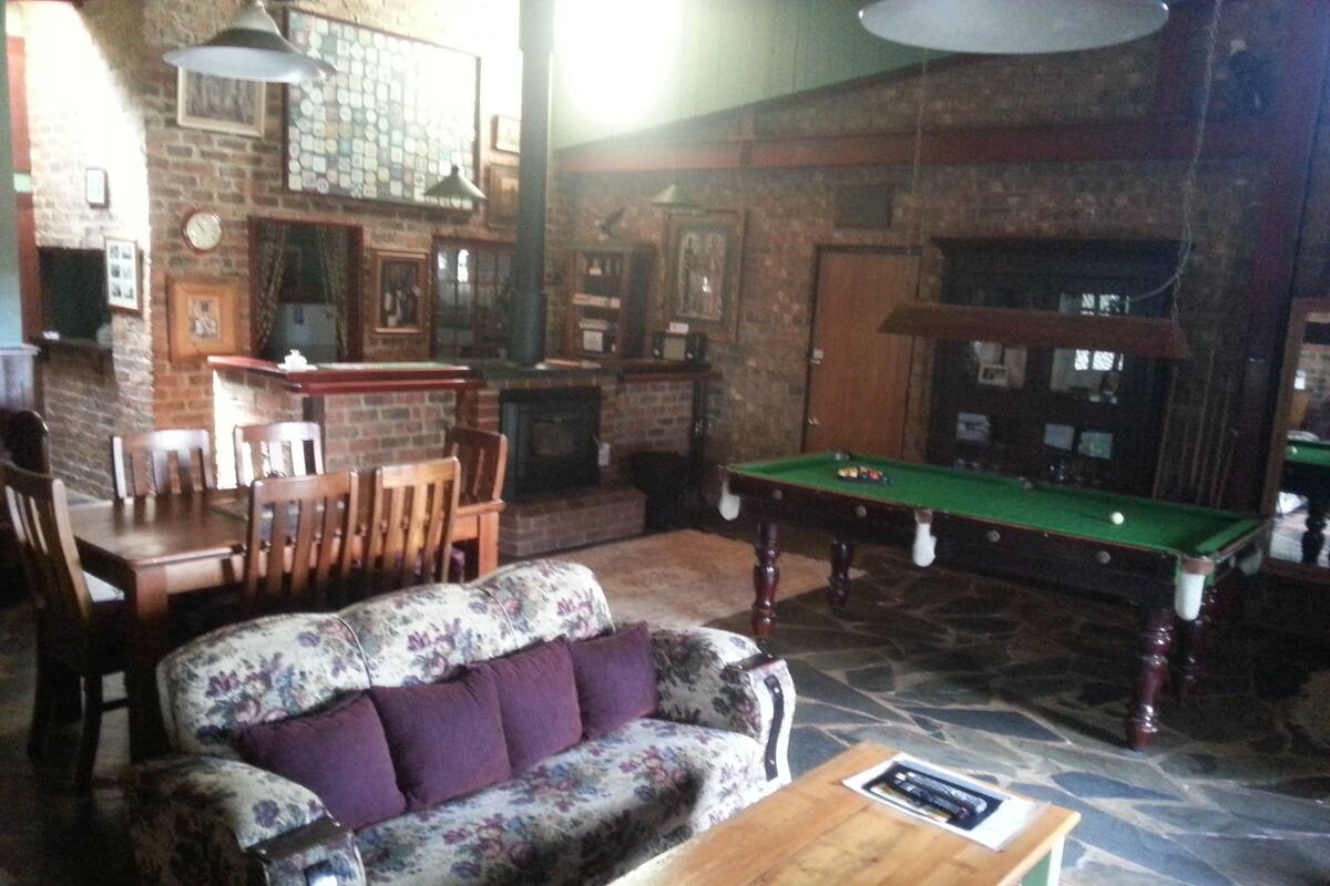 Um quarto aconchegante com mesa de bilhar, sofá e parede de tijolos.