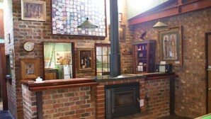 A room with a brick fireplace, a pool table, and various framed pictures on the walls. - Eagle Foundry Bed & Breakfast (Gawler)
