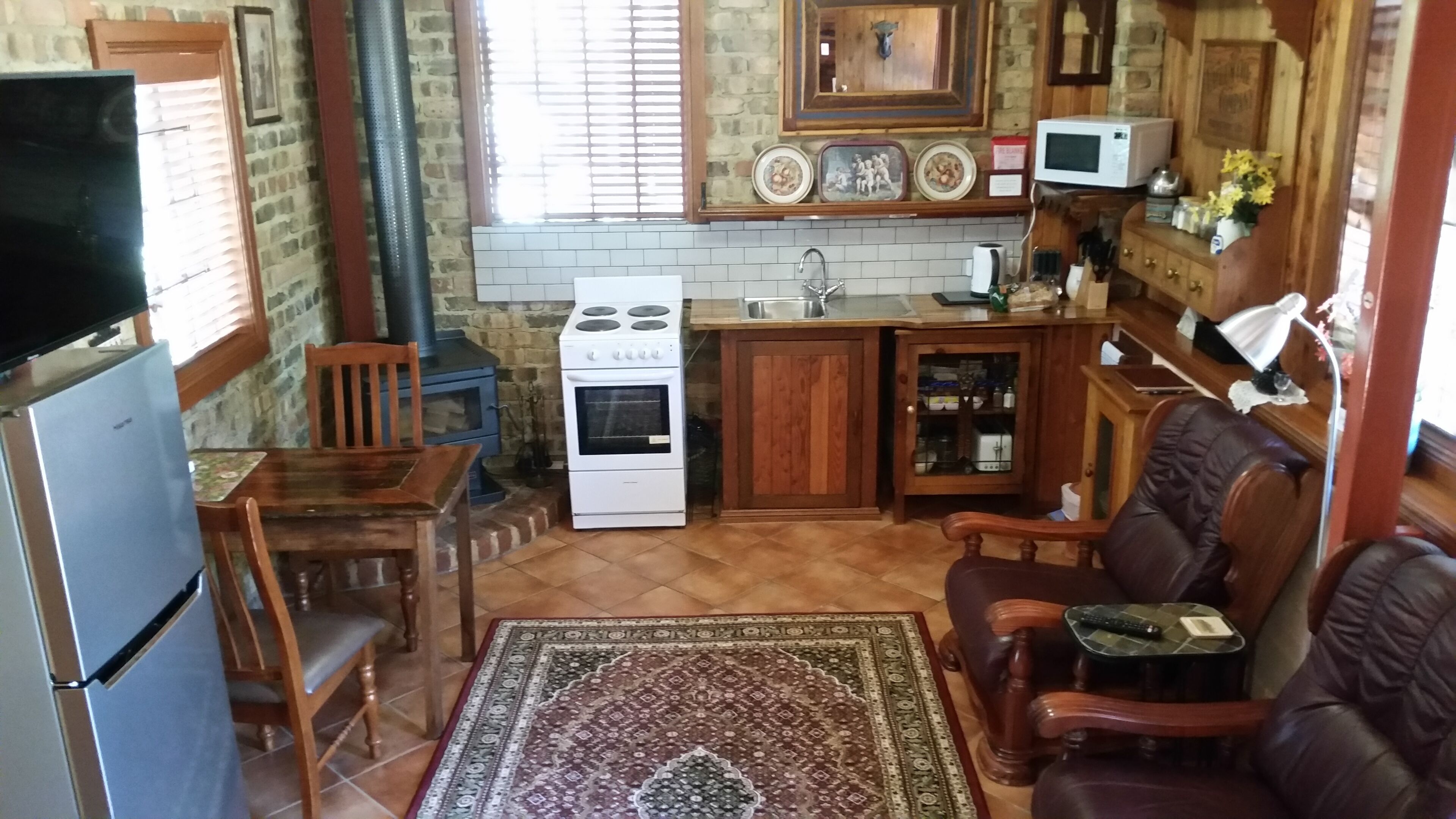 A compact kitchen with a stove, sink, and microwave. There is a dining area with a table and chairs, and a living area with a sofa.