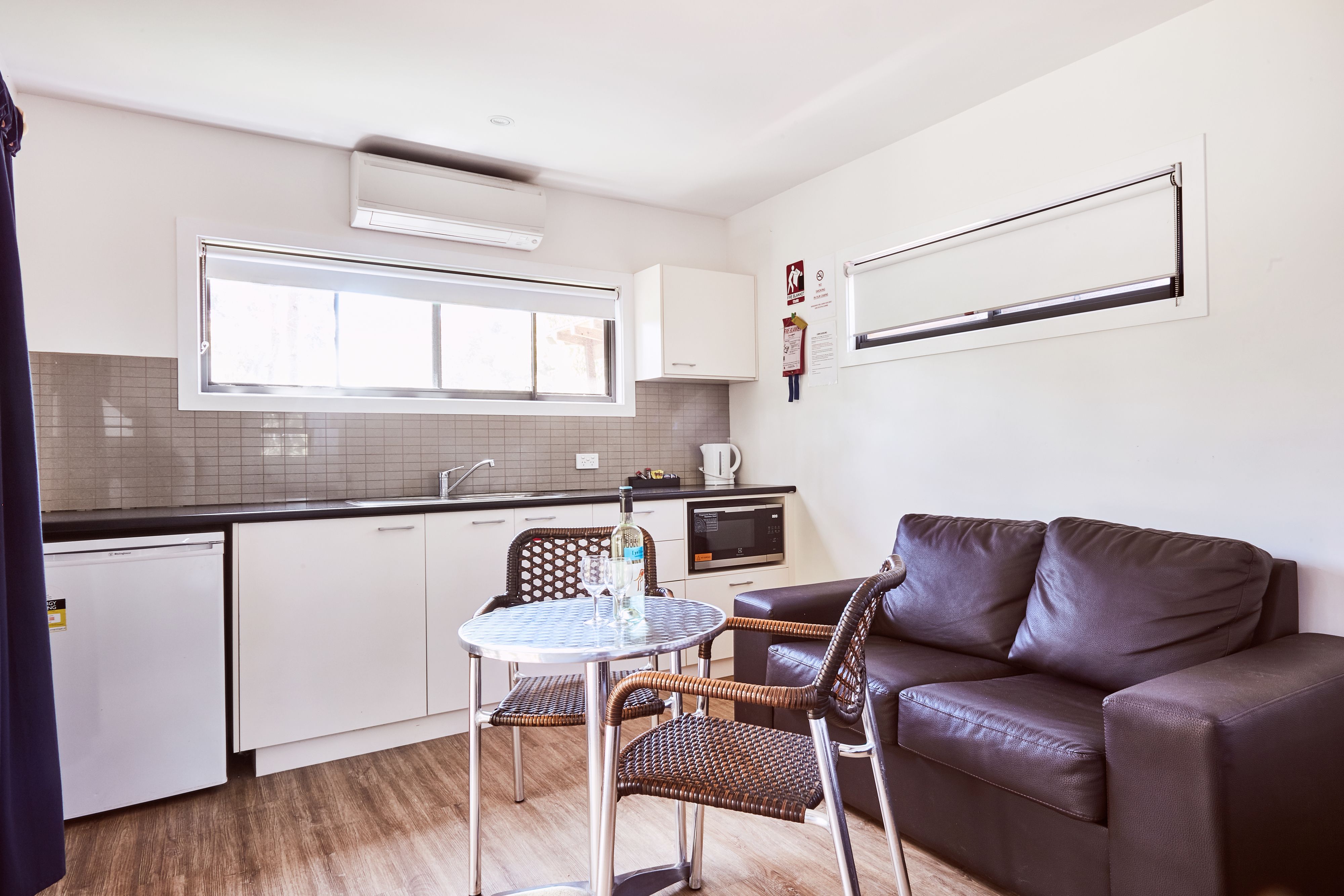Une cuisine compacte avec un coin repas, comprenant un petit réfrigérateur, un four à micro-ondes et une table à manger avec des chaises.
