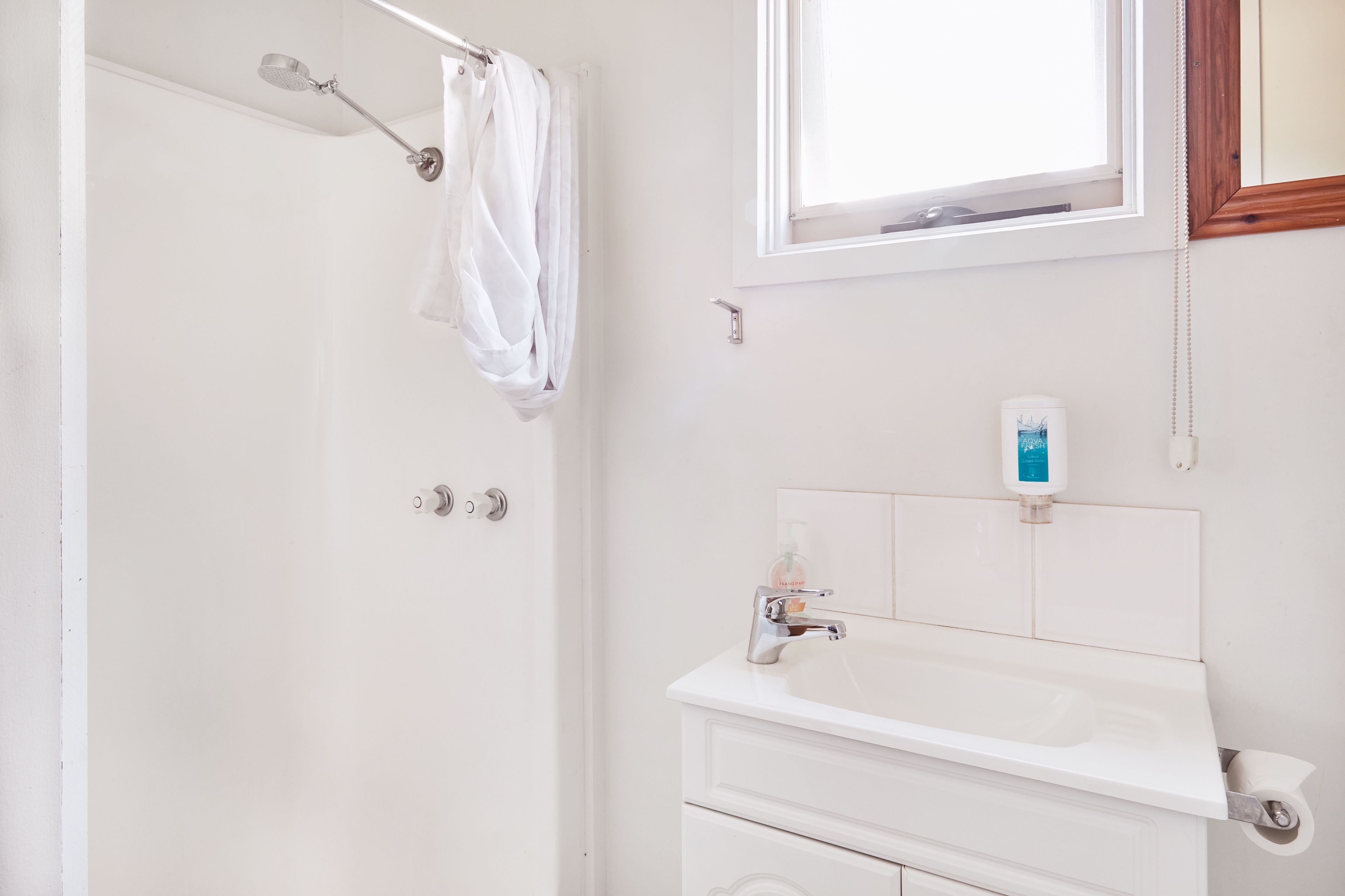 Baño con ducha, lavabo y ventana.