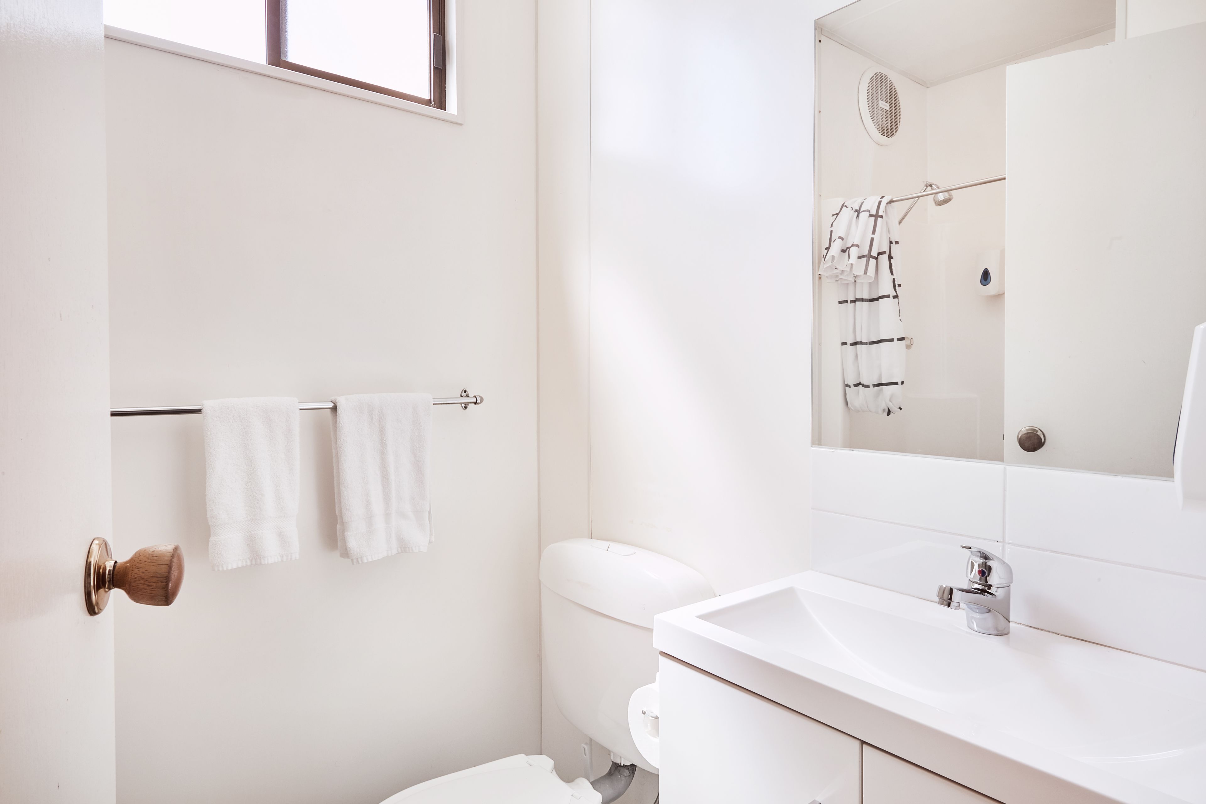Een badkamer met een wit toilet, een wastafel en een handdoekhouder.