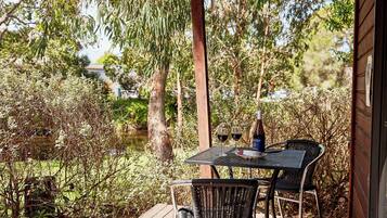 An outdoor seating area with a table and chairs, overlooking a body of water and surrounded by trees.