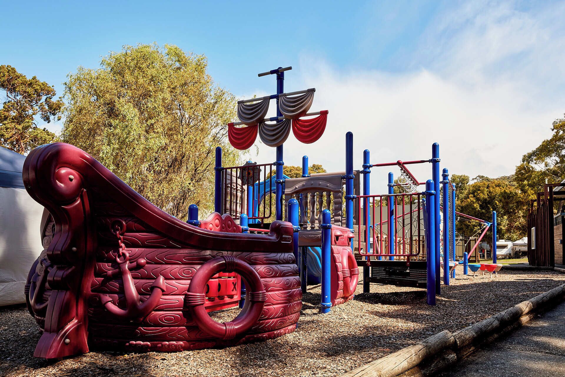 A playground with a ship-themed play structure, including slides and climbing areas.