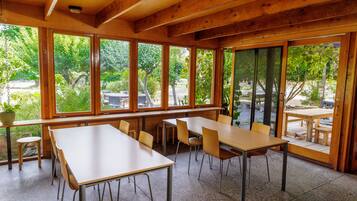 Un interior de madera con ventanas amplias, mesas y sillas dispuestas para comer.