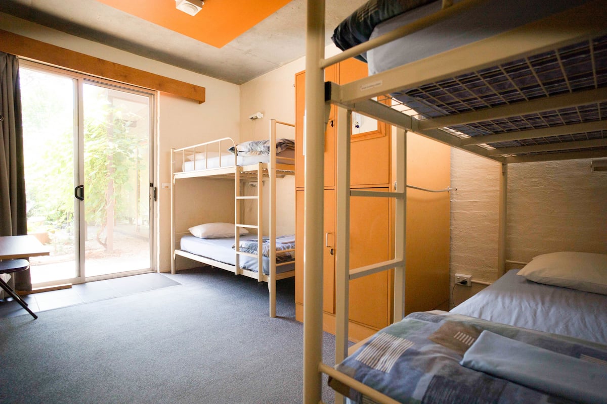 Un dormitorio con literas, un escritorio y una puerta corrediza de vidrio que da a un área exterior.