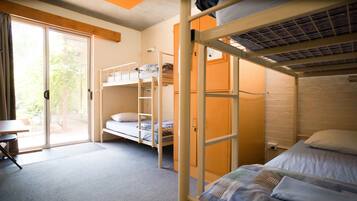 Un dormitorio con literas, un escritorio y una puerta corrediza de vidrio que da a un área exterior.