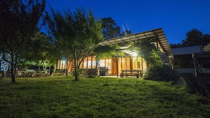 Una casa moderna con un porche cubierto, una zona de barbacoa y un césped bien cuidado.