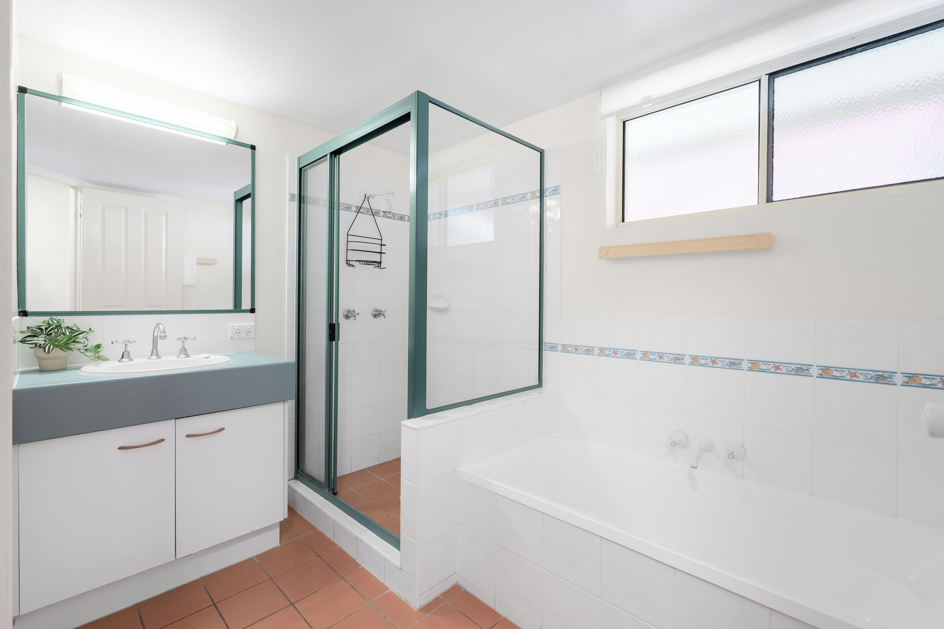 A modern bathroom with a glass-enclosed shower, a white bathtub, and a large mirror above the sink.