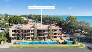 A multi-story building with balconies, a swimming pool, and a view of the sea. - Alexander Beachfront Apartments (Torquay)