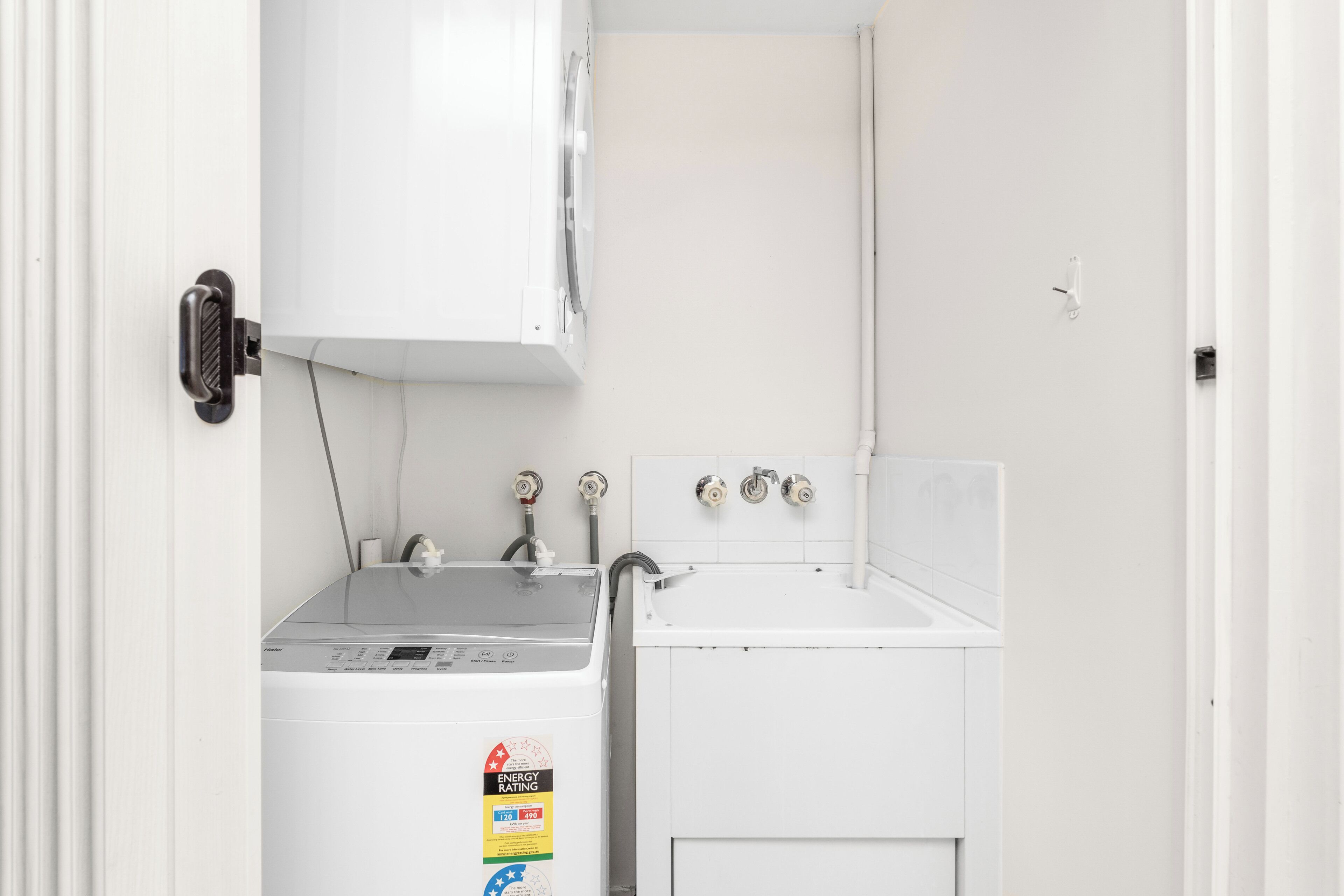 A laundry room with a washing machine and a dryer, both white, and a small sink.