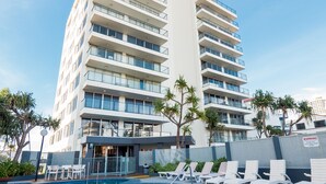 Un hotel con zona de piscina, varios pisos y cielo despejado.