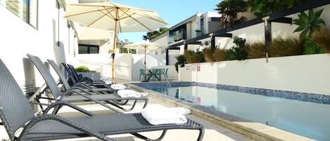A poolside area with lounge chairs, umbrellas, and a clear view of the pool.