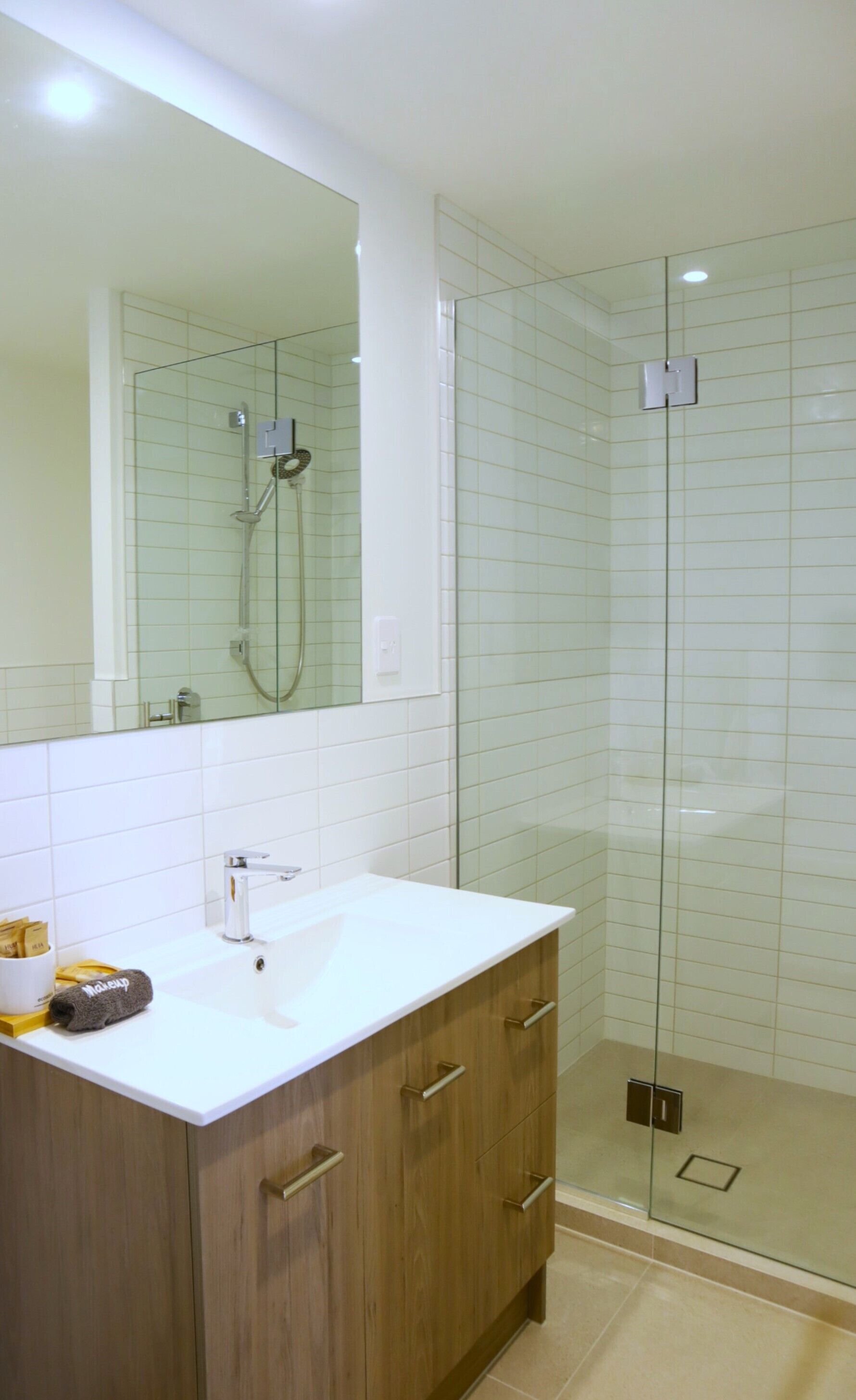 Une salle de bain moderne avec un meuble-lavabo blanc, une cabine de douche en verre et un grand miroir.