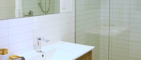 Une salle de bain moderne avec un meuble-lavabo blanc, une cabine de douche en verre et un grand miroir.