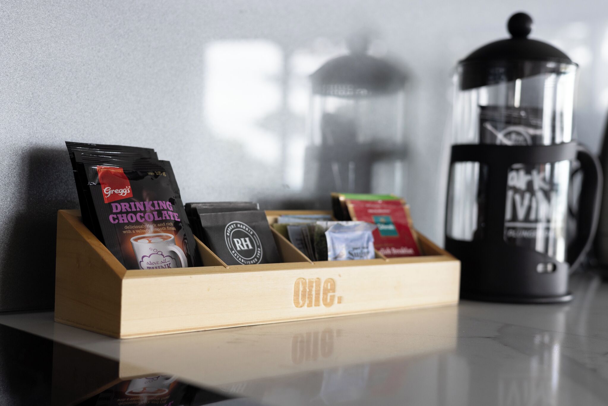 A coffee station with a coffee press and a wooden display of coffee pods.