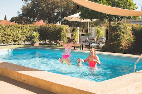 Una piscina al aire libre, sillones reclinables de piscina
